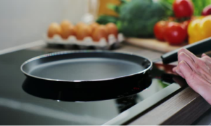 A pan rests on an induction cooker surface, demonstrating the appliance's ability to detect compatible cookware.