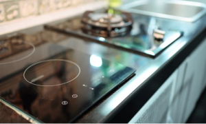 A sleek induction cooker sits beside a gas cooktop in a modern kitchen, highlighting its design and the need for residual heat awareness.